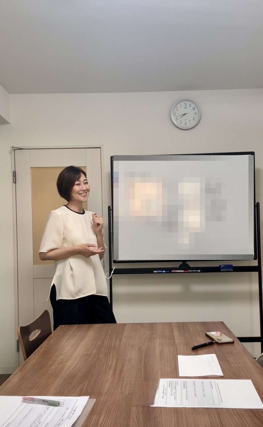 ホワイトボードの前で、笑顔で受講生に語りかける里実(Satomi)