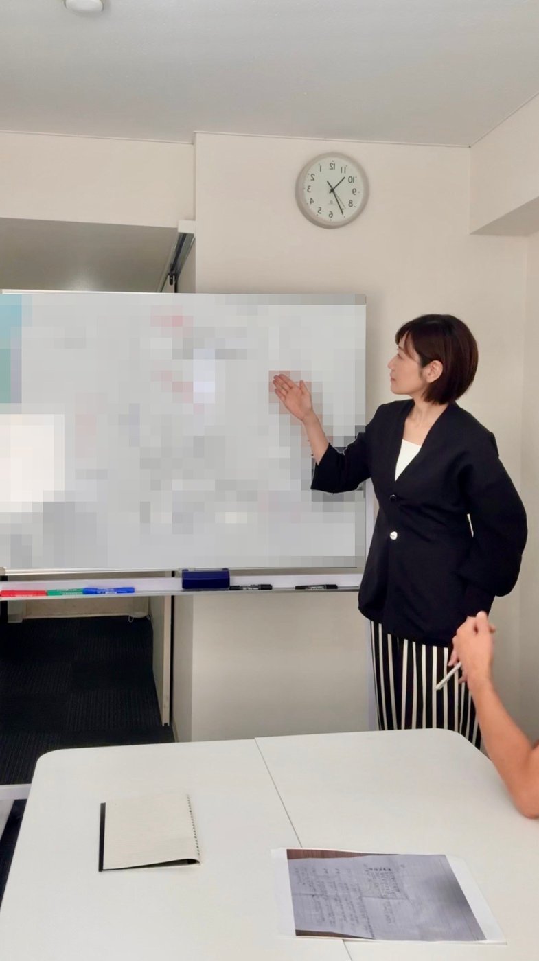 ホワイトボードを指しながら講義をする里実(Satomi)