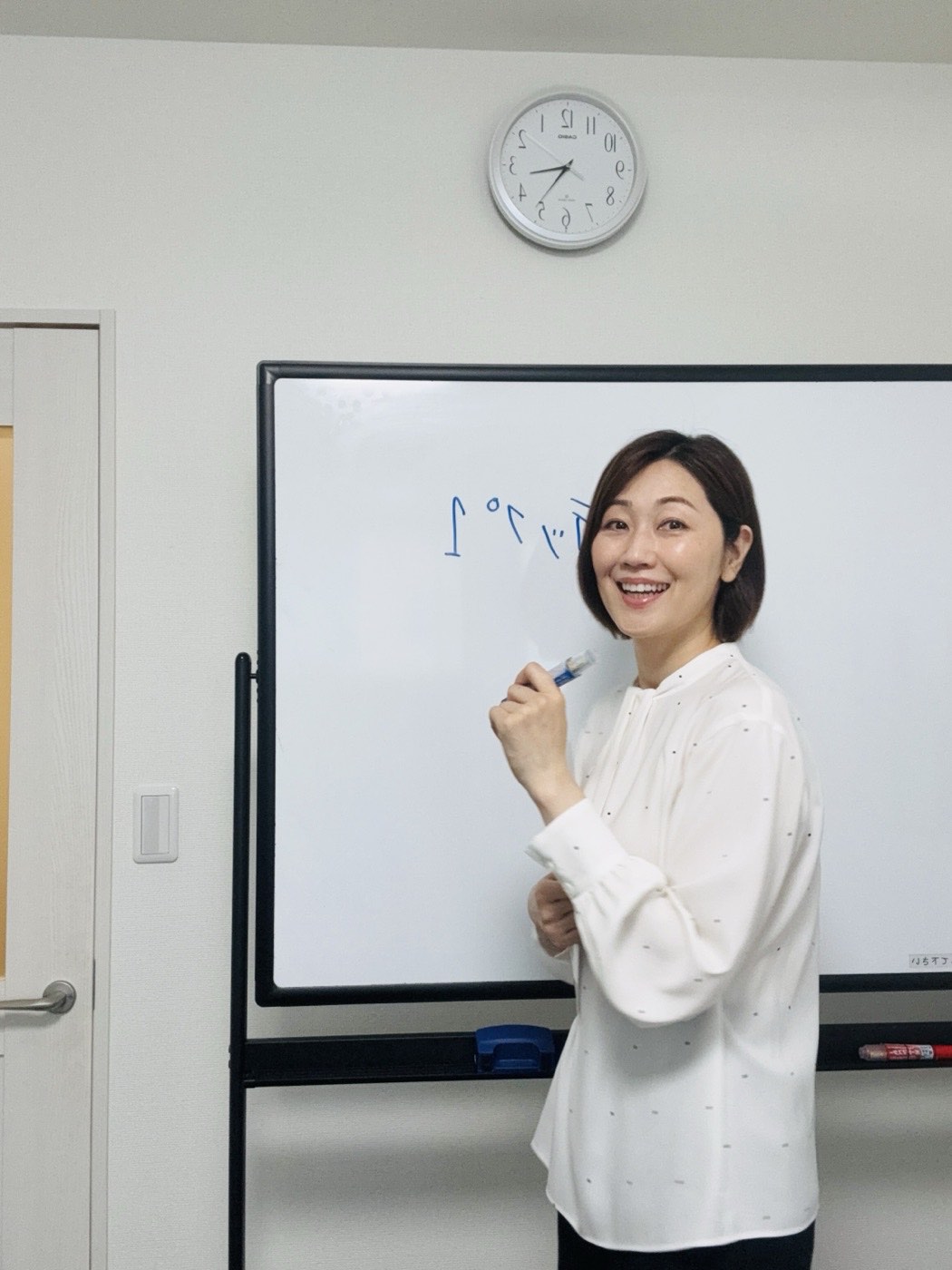 ホワイトボードの前で講義をする里実